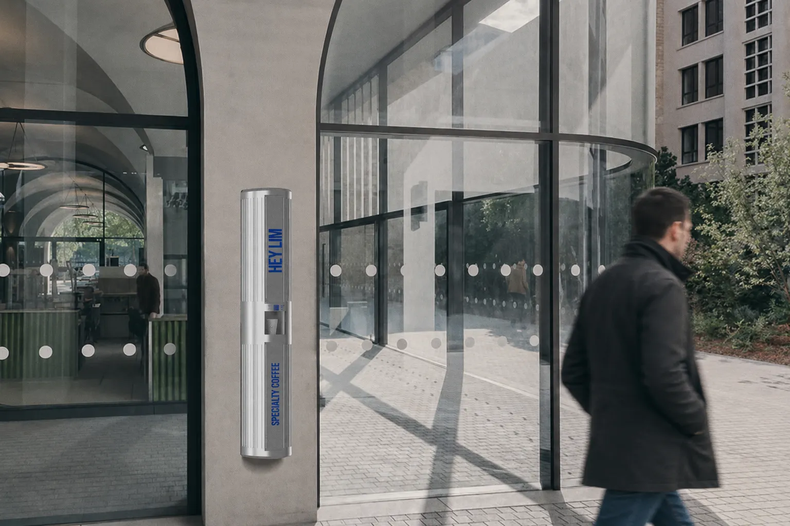 HEYLIM coffee pillar mounted beside curved glazing in a sunlit lobby